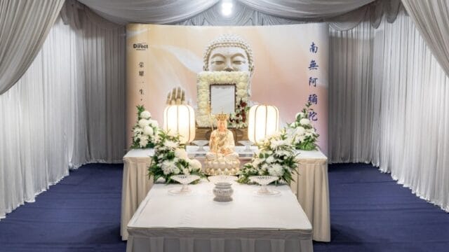 Buddhist funeral wake setup with traditional altar, floral arrangements, and themed backdrop.
