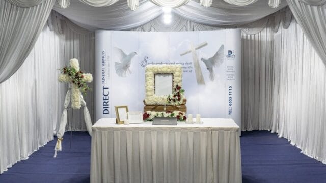 Modern Christian and Catholic funeral wake setup with white floral decor and elegant drapery.