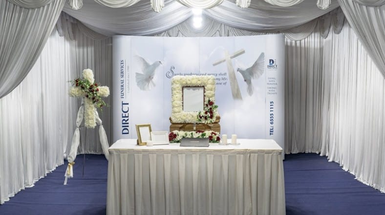 Modern Christian and Catholic funeral wake setup with white floral decor and elegant drapery.