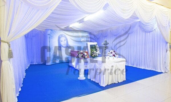Elegant Catholic funeral memorial setup with crucifix and premium floral arrangements by Fairprice Casket