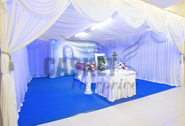 Elegant Catholic funeral memorial setup with crucifix and premium floral arrangements by Fairprice Casket
