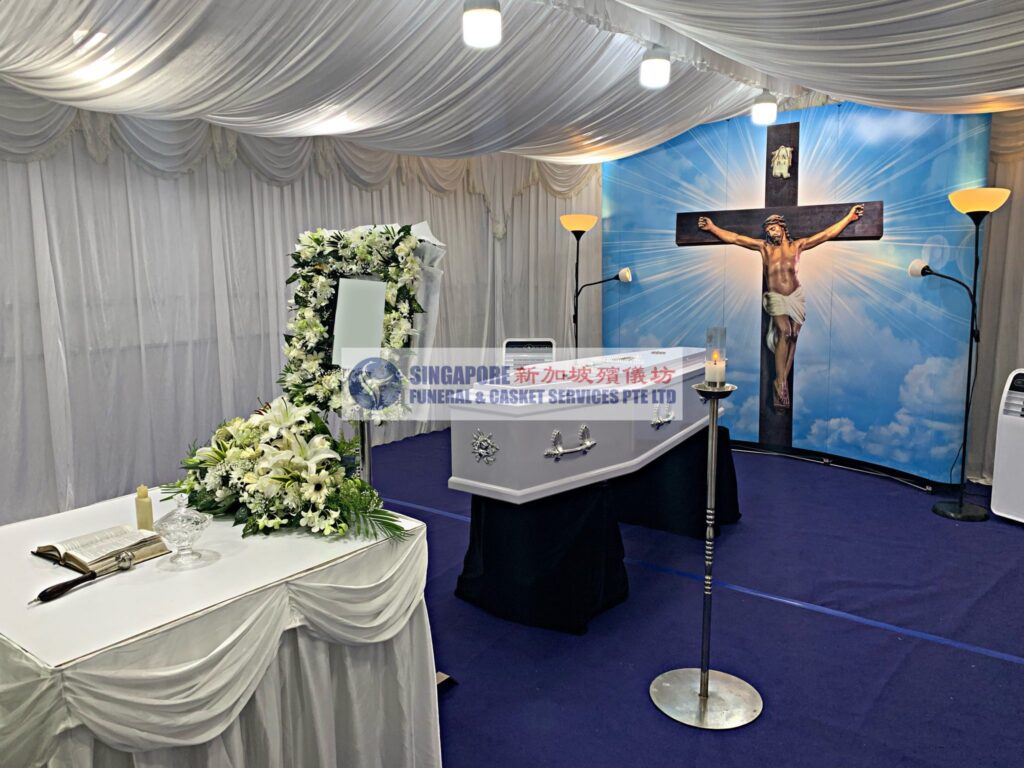 Catholic funeral wake setup by Singapore Funeral & Casket Services with cross backdrop and blue lighting