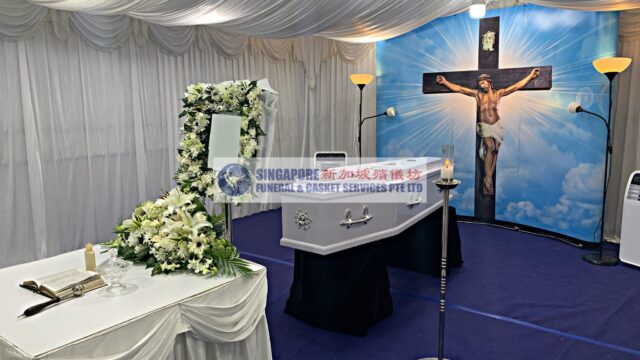 Catholic funeral wake setup by Singapore Funeral & Casket Services with cross backdrop and blue lighting