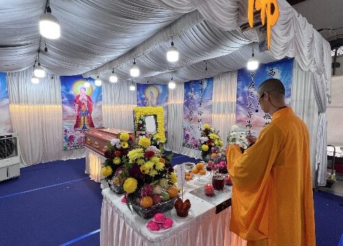 Buddhist funeral wake setup by Unity Casket with monk officiating beside a floral altar in Singapore