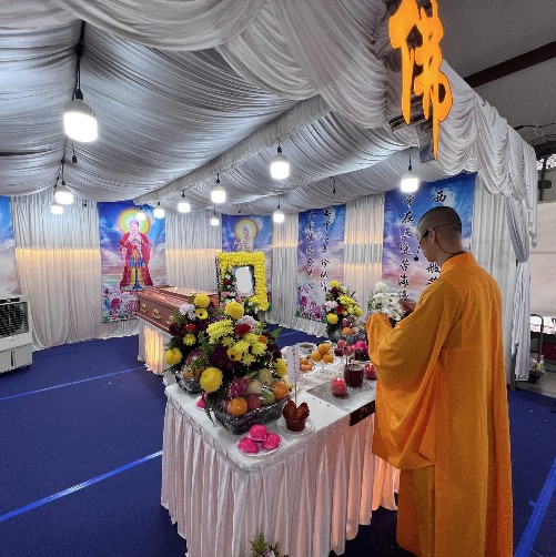 Buddhist funeral wake setup by Unity Casket with monk officiating beside a floral altar in Singapore